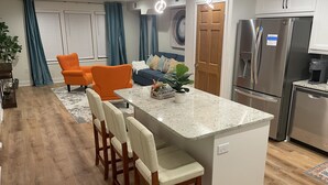 A modern kitchen with a central island, stainless steel appliances, and a seating area with orange chairs. - Penthouse Suite—Steps from Mayo Clinic Hospital (Rochester)