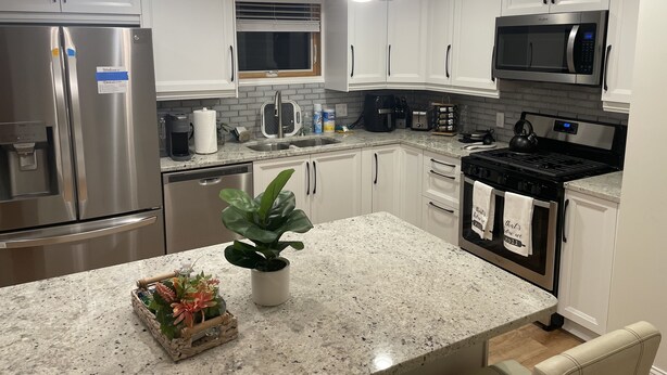 A modern kitchen with stainless steel appliances, white cabinetry, granite countertops, and pendant lighting. - Penthouse Suite—Steps from Mayo Clinic Hospital (Rochester)