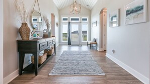 A hallway with a dark wooden console table, wicker baskets, a patterned rug, and a large mirror. - SEASHELLS BY THE SEASHORE - Beautiful beachfront, sleeps 12! (Port Bolivar)