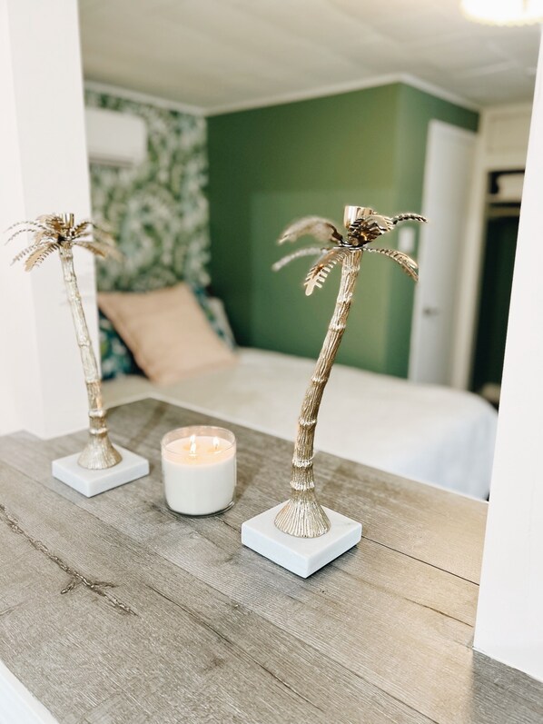 A wooden table with two decorative palm tree figures and a lit candle.