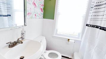 Een bad/douchecombinatie, een haardroger, handdoeken, toiletpapier