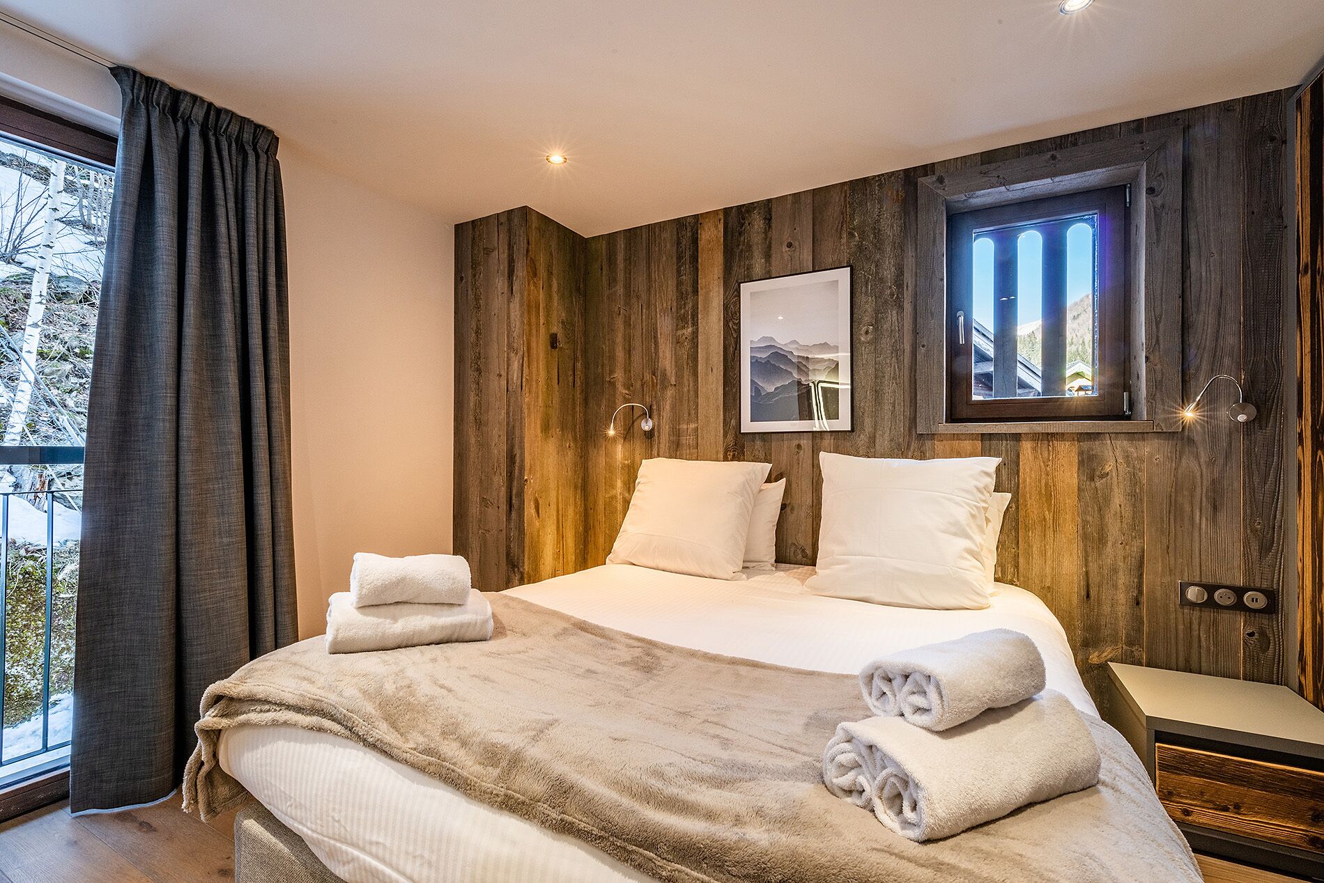 Een slaapkamer met een groot bed, twee kussens, een deken en twee handdoeken.