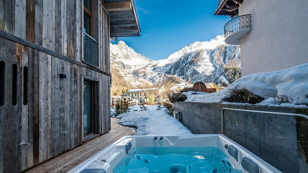 A wooden building with a hot tub in the foreground, a snowy mountain backdrop, and a clear sky. - EYONG - Premium apartment with sauna and hot tub (Chamonix-Mont-Blanc)