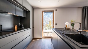 A modern kitchen with a large window, wooden flooring, and a built-in oven. - EYONG - Premium apartment with sauna and hot tub (Chamonix-Mont-Blanc)