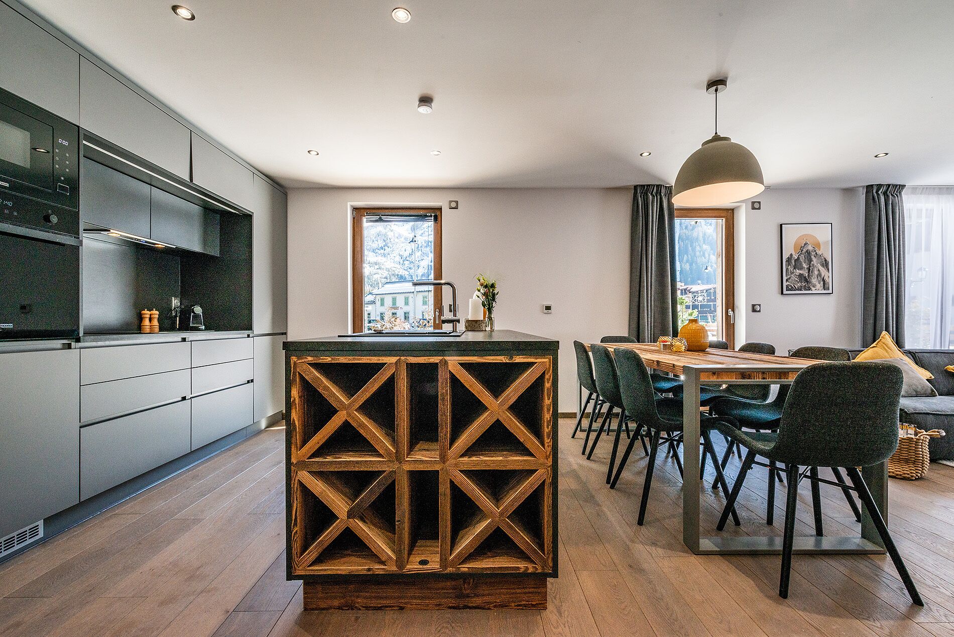 Une cuisine moderne avec un îlot central, un coin repas avec des chaises et une vue sur un paysage enneigé par les fenêtres.