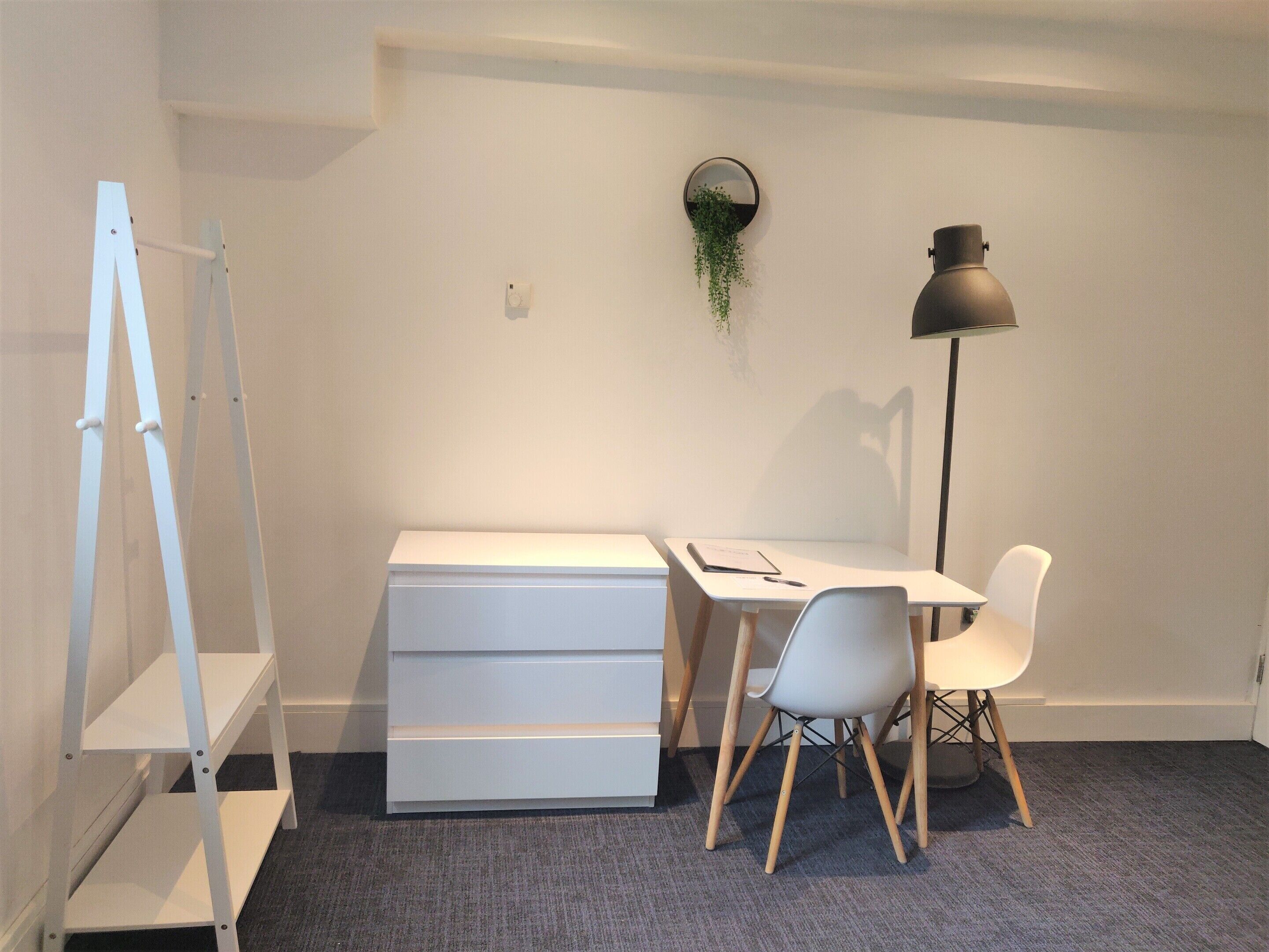 A minimalist office space with a desk, chair, and shelving unit.