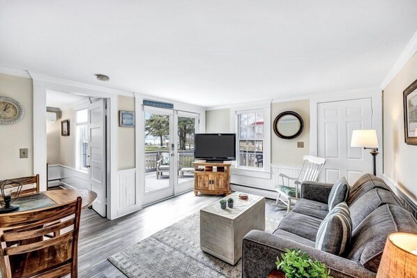 A living room with a TV, sofa, coffee table, and dining area.