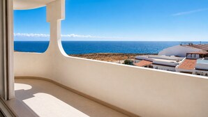 A balcony with a view of the sea and buildings.