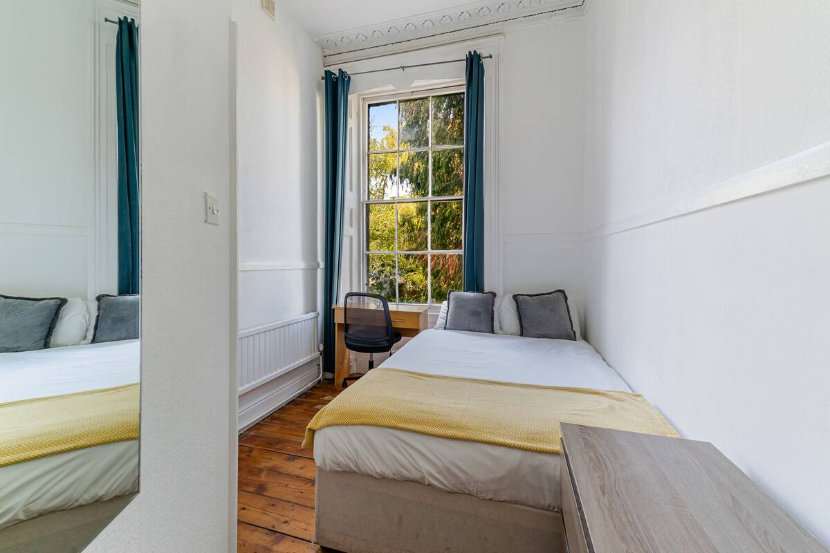 Een kamer met twee bedden, een bureau en een raam met gordijnen.