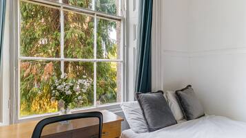 Una habitación con una cama, un escritorio y una silla. Hay una ventana con cortinas.