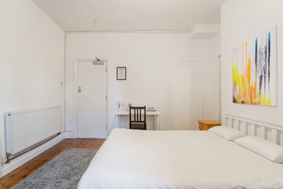 Een slaapkamer met een groot bed, een bureau en een stoel.