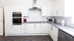 A modern kitchen with white cabinets, a built-in oven, a coffee maker, a microwave, and a dishwasher.