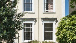 A multi-story building with white-framed windows and a stone wall in front.