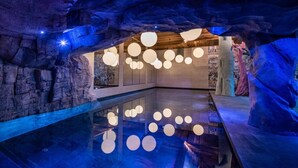 An indoor swimming pool with a modern design, featuring a stone wall and wooden ceiling. - Wifi, ski-in/ski-out & foot of the slopes, fitness, swimming pool, sauna, hammam, balcony, tv (Val-d'Isère)