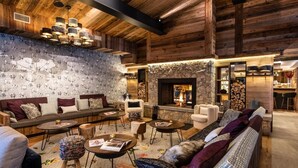 A cozy living room with a fireplace, wooden walls, and a patterned wallpaper. - Wifi, ski-in/ski-out & foot of the slopes, fitness, swimming pool, sauna, hammam, balcony, tv (Val-d'Isère)