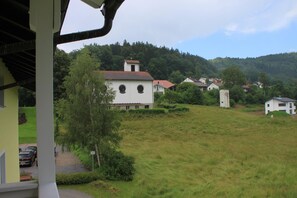 A rural village with houses surrounded by greenery and hills.