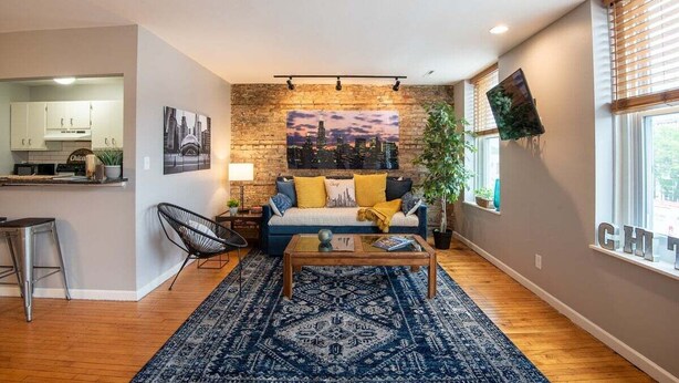 A modern living room with a sofa, coffee table, and a cityscape painting on the wall. - The Downtown Trifecta |Large & Unique Lodging | Perfect for Group Stays |Main St |Parking Included (Lake Geneva)