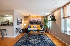 A modern living room with a sofa, coffee table, and a cityscape painting on the wall.