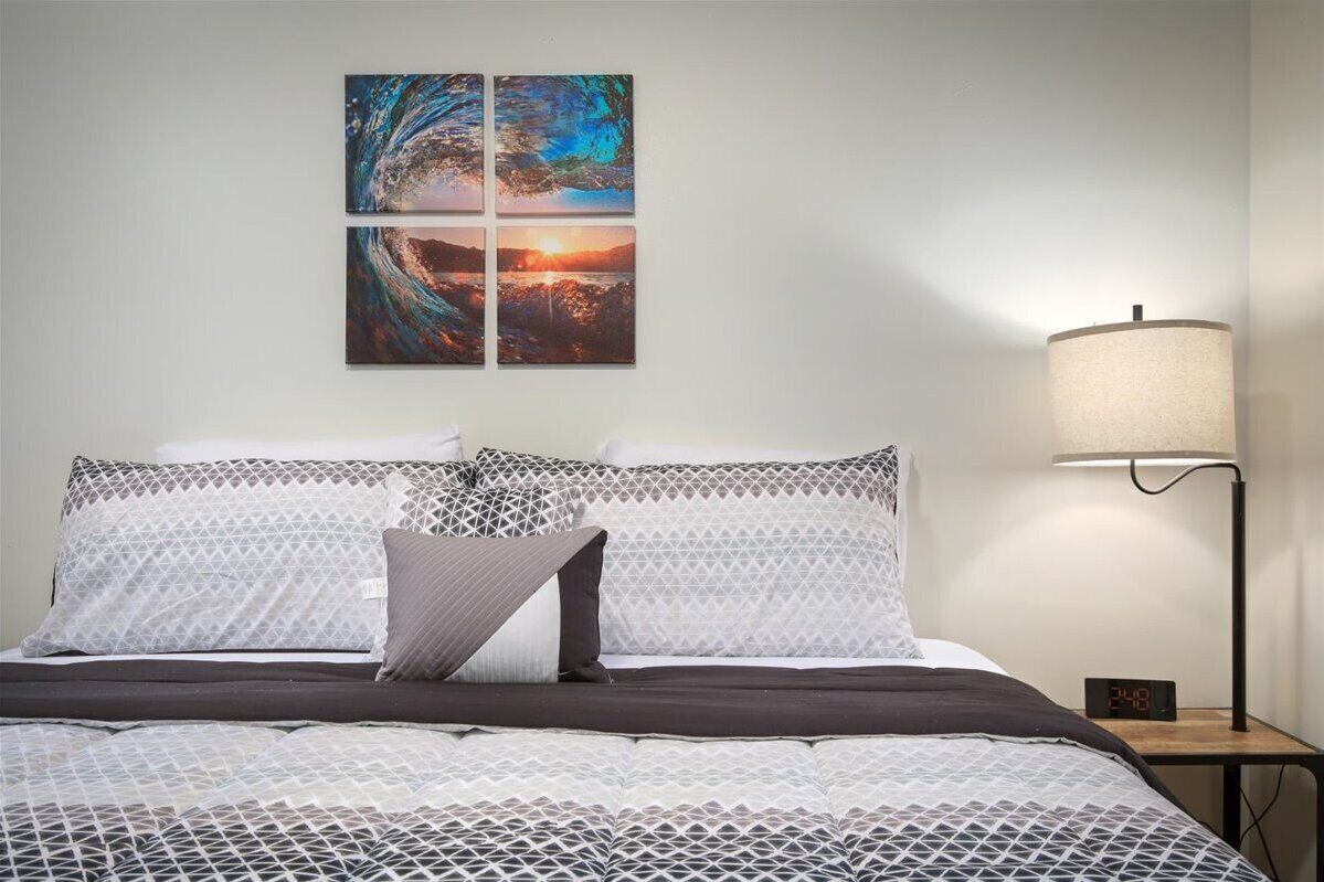 A neatly made bed with patterned bedding, a bedside lamp, and a digital clock on a nightstand.