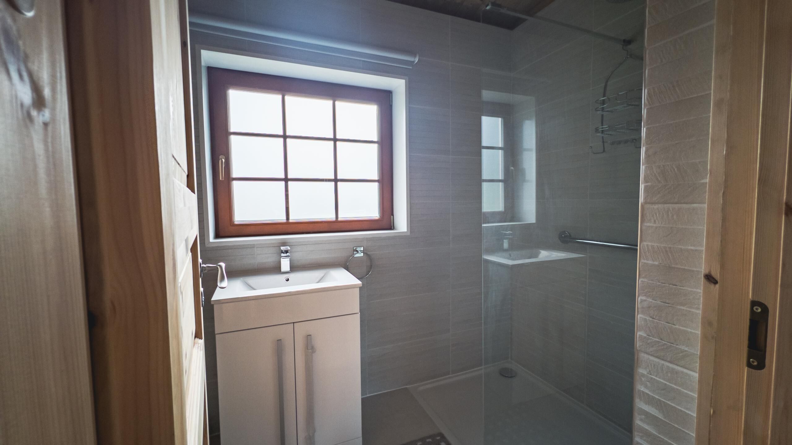 A bathroom with a window, a sink, and a shower.