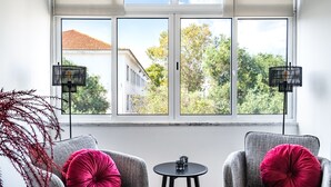 A room with a large window, two grey armchairs with red cushions, a small round table, and two black floor lamps. - Sapphire Apartment, AC, Wifi !new! (Lisboa)
