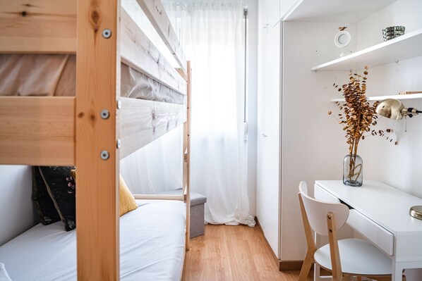 A compact room with a bunk bed, a desk, and a chair.