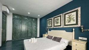 Ein Schlafzimmer mit einem großen Bett, einem Kleiderschrank und drei gerahmten Pflanzenbildern an der Wand.