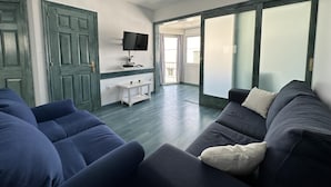 Ein modernes Wohnzimmer mit einem dunkelblauen Sofa, einem weißen Couchtisch und einem an der Wand montierten Flachbildfernseher.