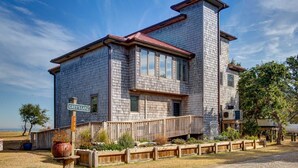 Une maison à deux étages avec une façade en bois, un toit rouge et une terrasse en bois.