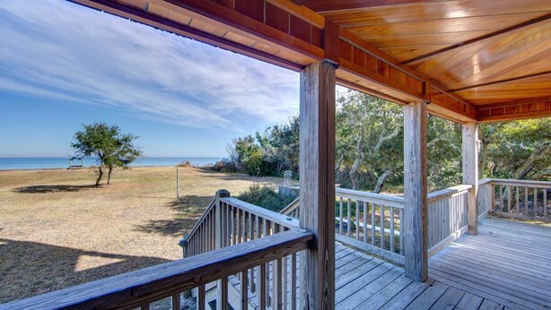 Une terrasse en bois offrant une vue sur la plage et l’océan.