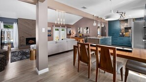 A modern kitchen with a dining area, featuring a large island, pendant lighting, and a built-in oven. - The Sinatra - Fun, 5BD Home! Huge Pool! Game Room! (Round Rock)