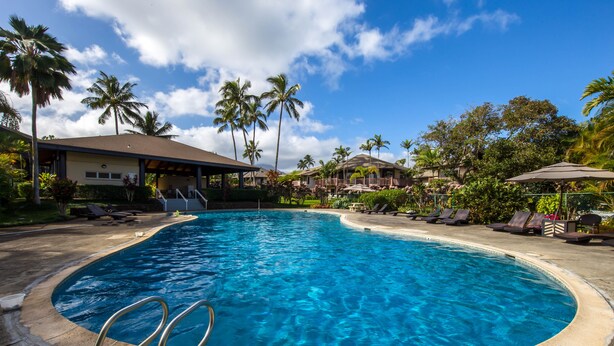 A swimming pool with lounge chairs and palm trees. - Stylish and Spacious Condo - A/C in 2 Bedrooms, Huge Lanai, Great Location (Princeville)