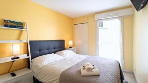 Een hotelkamer met een bed, nachtkastjes, een televisie en een raam.