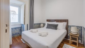 Un dormitorio con una cama, una mesita de noche, una ventana y vistas al exterior.
