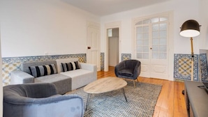 Una sala de estar con sofá, sillones, una mesa de centro y una lámpara.