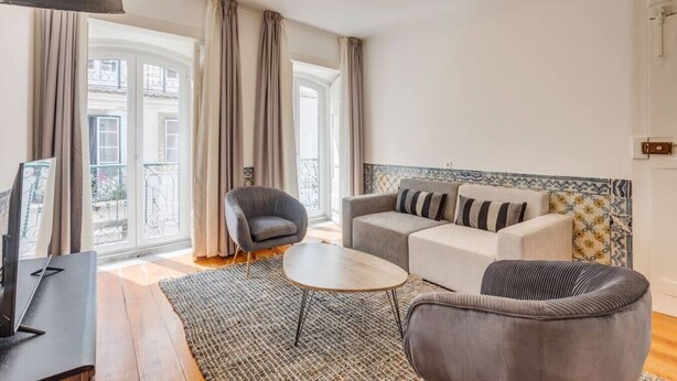 Una sala de estar moderna con un sofá, sillones, una mesa de centro y un televisor.