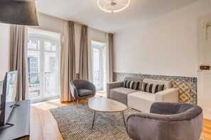 A modern living room with a sofa, armchairs, a coffee table, and a TV.