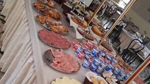 A buffet table with various food items and utensils, including pastries, meats, and condiments.
