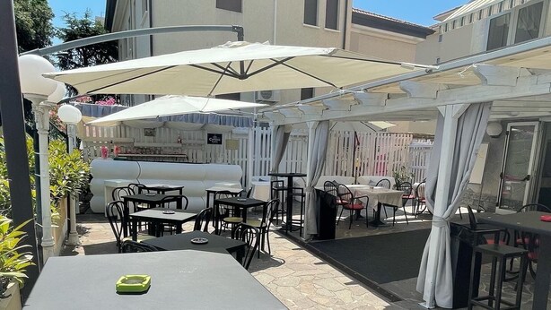 An outdoor patio area with stone flooring, tables, and umbrellas.