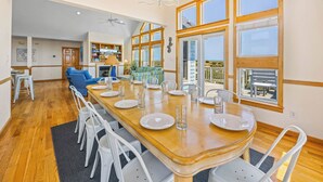 A spacious dining area with a wooden table set for four, surrounded by white chairs. - Premier Oceanfront Dog Friendly Home w/ Private Pool, Hot Tub, Game Room (Salvo)