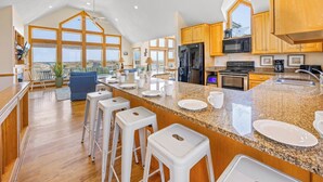A spacious kitchen with a large island, wooden cabinets, and a view of the outdoors. - Premier Oceanfront Dog Friendly Home w/ Private Pool, Hot Tub, Game Room (Salvo)