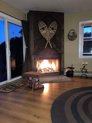 A living room with a fireplace, a sliding glass door, and a rug.