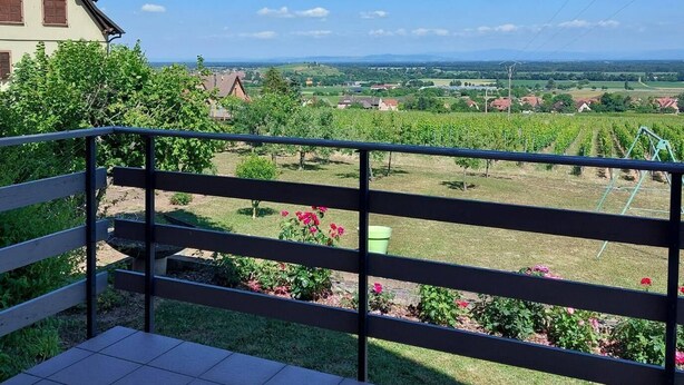 A balcony with a view of a rural landscape, including fields and a distant building. - Appartement (Gueberschwihr)