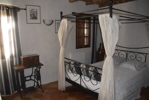 A four-poster bed with a white canopy, a wooden nightstand, a mirror, and a radiator on the wall. - 3-star gite - fiber - swimming pool 15x7 (Montcuq-en-Quercy-Blanc)