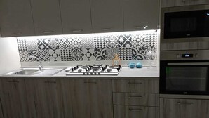 A modern kitchen with a patterned backsplash, a gas stove, a sink, and built-in ovens. - moon house (San Cesario di Lecce)