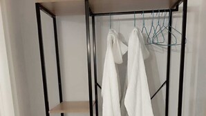 A black metal wardrobe with three shelves and a hanging rod, containing white clothing. - moon house (San Cesario di Lecce)