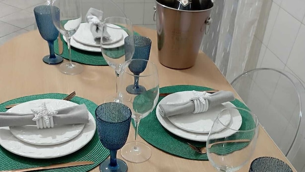A dining table set with green placemats, white plates, and blue glassware. - moon house (San Cesario di Lecce)
