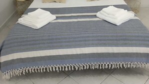 A neatly made bed with a striped blanket and two folded towels, a dark headboard, and a painting of a wave on the wall. - moon house (San Cesario di Lecce)