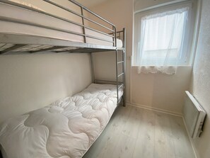 A bunk bed room with a window and radiator.