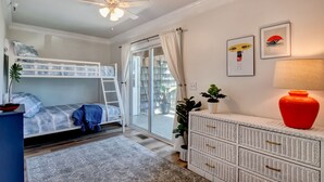 A bedroom with a bunk bed, a ceiling fan, a sliding glass door, a white dresser, and a red lamp. - Family Oasis 1 block from the beach near Boardwalk (Carolina Beach)